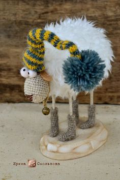 a knitted sheep with a yellow and blue hat on it's head is standing next to a small stuffed animal