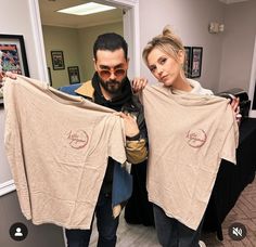 the man and woman are holding up shirts