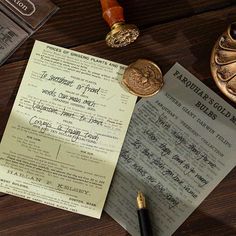 a piece of paper sitting on top of a wooden table next to a pen and some coins