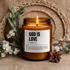 a candle sitting on top of a wooden table next to flowers and a wreath with the words god is love