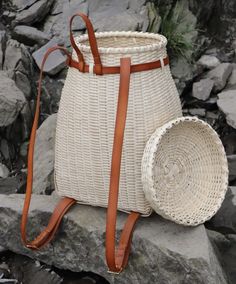 a white wicker basket sitting on top of a rock next to a brown leather strap