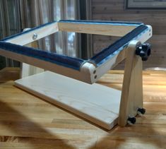 a wooden table with a glass top and wheels attached to the legs, sitting on a hard wood floor