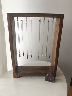 a wooden frame with several necklaces hanging from it's sides on a table