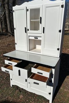 a white cabinet with drawers in the grass