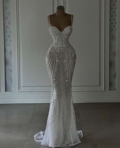 a wedding dress on display in front of a white wall with an open back and beading