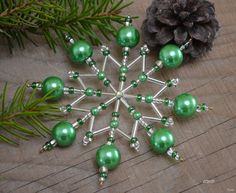 a green christmas ornament sitting on top of a wooden table next to pine cones