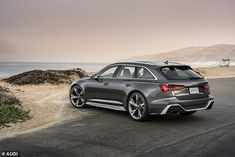 an audi car parked on the side of the road near the ocean and sand dunes