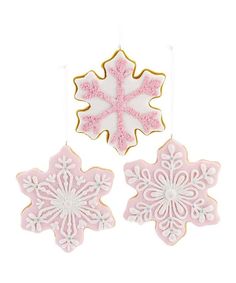 two pink and white snowflake cookies hanging from strings with icing on them