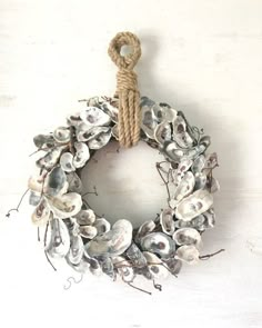 a wreath made out of seashells hanging on a wall with a rope attached to it