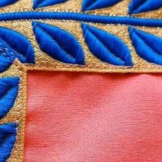 close up view of blue and red fabric with gold embroidery on the bottom half of it