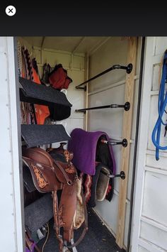 the inside of a horse trailer with several saddles and hats hanging on the wall