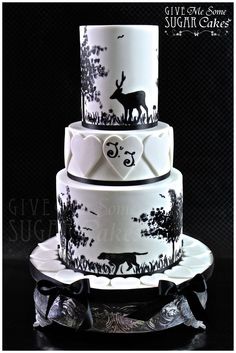 a three tiered cake with black and white designs on the side, topped with a heart