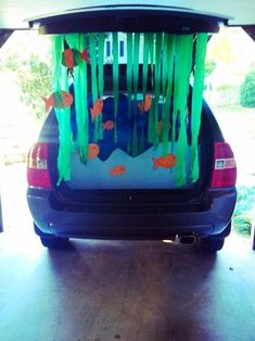 the back end of a car decorated with paper streamers, fish and seaweed