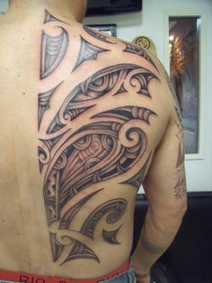 the back of a man's shoulder with an intricate tattoo design on it