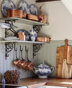 the shelves in this kitchen are filled with pots and pans, cutting boards, and utensils