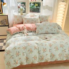 a bed with flowers on the comforter and pillows in front of a large window