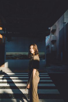 a woman is standing in the middle of an empty crosswalk with her hand on her hip