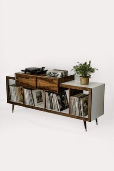 an old record player sitting on top of a wooden cabinet next to a potted plant