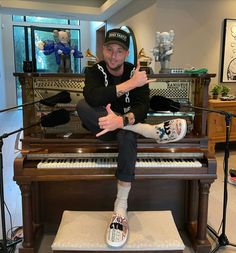 a man sitting on top of a piano giving the thumbs up