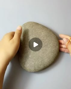 someone is holding a rock with a video playing button on the front and side of it