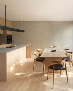 a dining room and kitchen area with wood flooring, white walls and wooden furniture