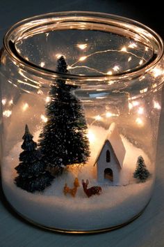 a glass jar filled with snow and lit up christmas trees