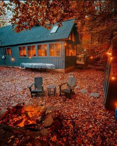 an outdoor fire pit in front of a cabin with chairs and lights on the patio