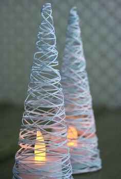 two wire christmas trees sitting on top of a table next to each other with candles in them