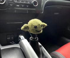 a crocheted baby yoda head sitting on top of a car steering wheel