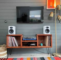 an entertainment center with speakers and records in front of a flat screen tv mounted on the wall