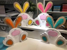 three easter bunnies sitting on top of a white shelf in front of a bookcase