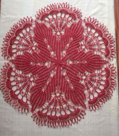 a red doily on a white tablecloth with an intricate design in the center