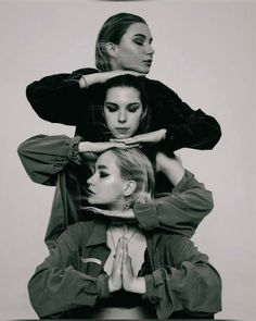 three women sitting on top of each other with their hands in the air and one woman covering her face