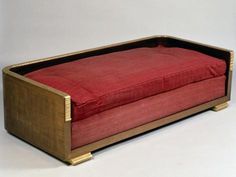 an old wooden couch with red fabric on it's back and seat cushion in the middle