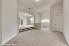 an empty living room with carpeted flooring and stairs leading to the front door