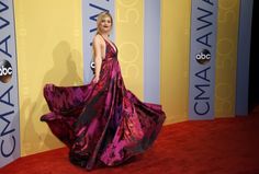 a woman in a purple dress standing on a red carpet