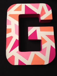 the letter g is made out of pink and orange geometric shapes with white letters on it