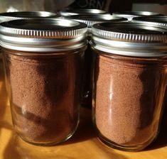 four jars filled with brown stuff sitting on top of a wooden table