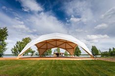 a large white tent sitting on top of a lush green field next to a lake