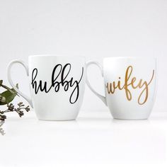 two coffee mugs with the words hubby and wife painted on them next to flowers