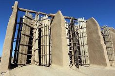 an adobe - style structure made out of wood and stone with lattices on the sides