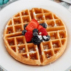 a waffle topped with berries and powdered sugar