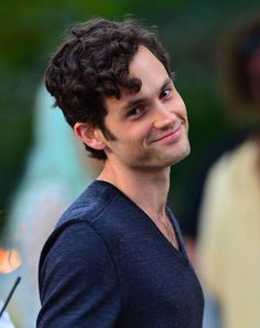 a man with curly hair is smiling at the camera