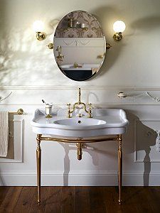 a white sink sitting under a mirror next to a wall mounted faucet in a bathroom