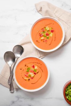 two bowls of carrot soup on a table