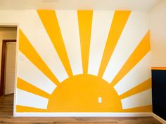 an orange and white sun painted on the side of a wall in a room with hard wood floors