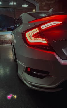 the rear end of a white car in a parking garage with its brake lights on