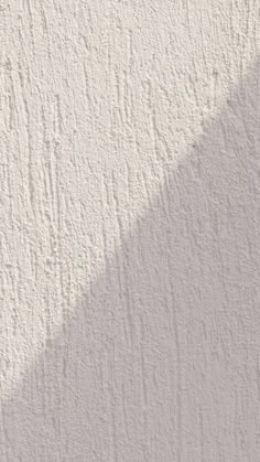 the shadow of a person's hand is cast on a stucco wall with white paint