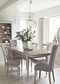 a dining room table with chairs and a vase filled with flowers on top of it