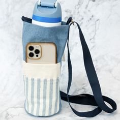 a cell phone in a bag on a marble surface with a blue and white striped strap